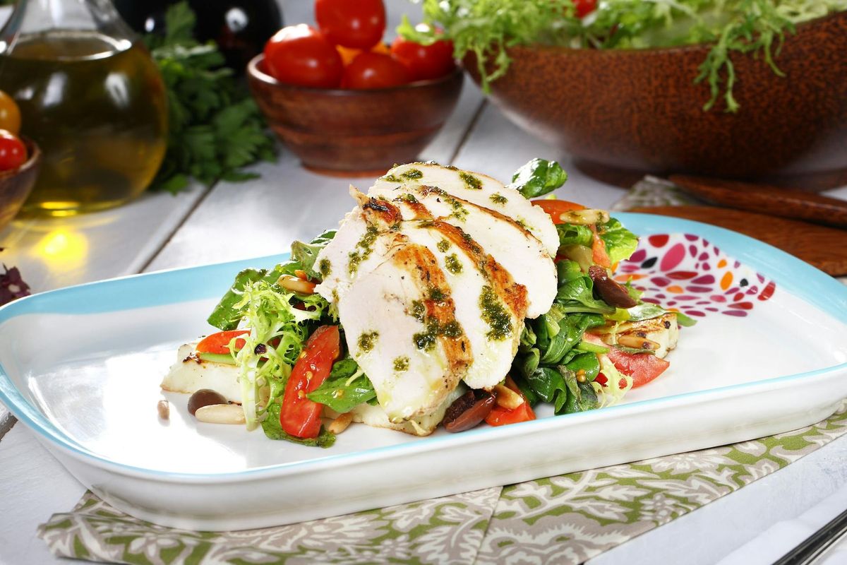Delicious grilled chicken salad with fresh vegetables on a decorative plate.