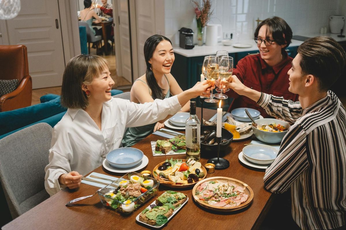 A lively gathering of friends sharing a meal and raising wine glasses.