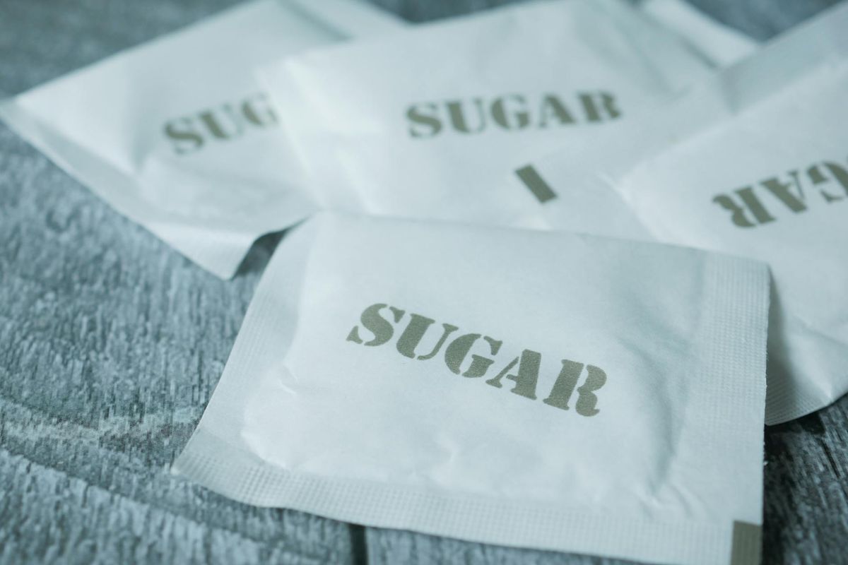 A detailed view of white sugar packets scattered on a rustic surface.