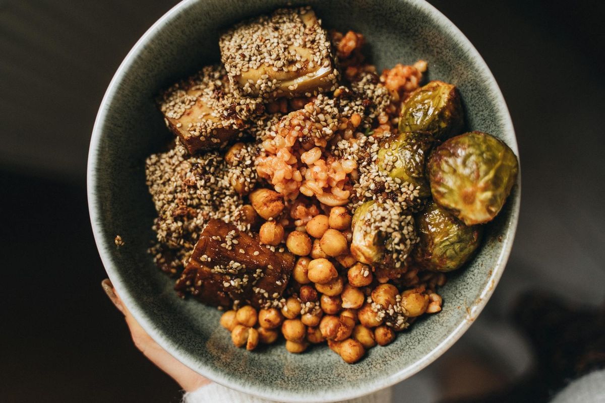Delicious vegan bowl featuring chickpeas, Brussels sprouts, and eggplant with sesame seeds.