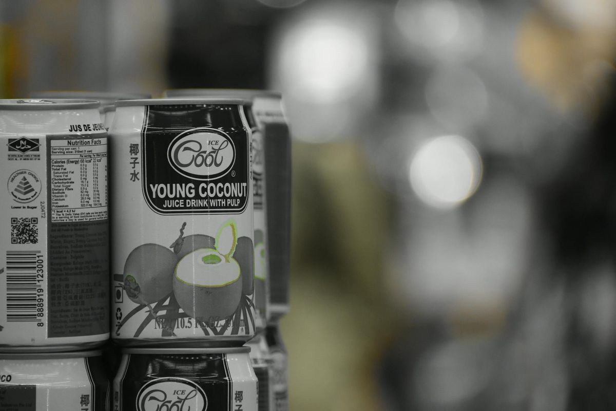 A stack of young coconut juice cans on a shelf with a retail background.