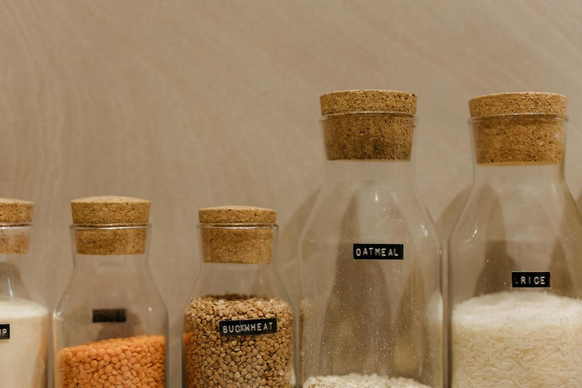 Various grains in labeled glass jars for kitchen storage.