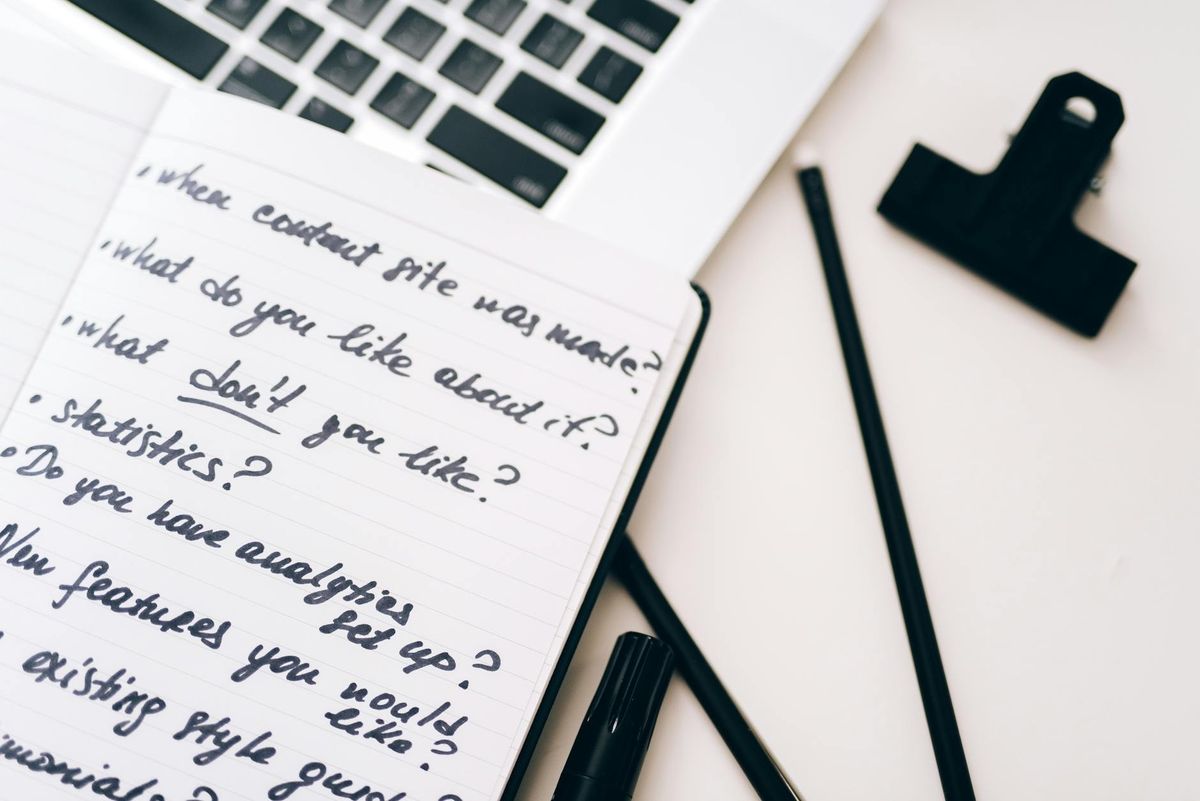 A close-up view of a notebook with handwritten notes alongside a laptop for planning.