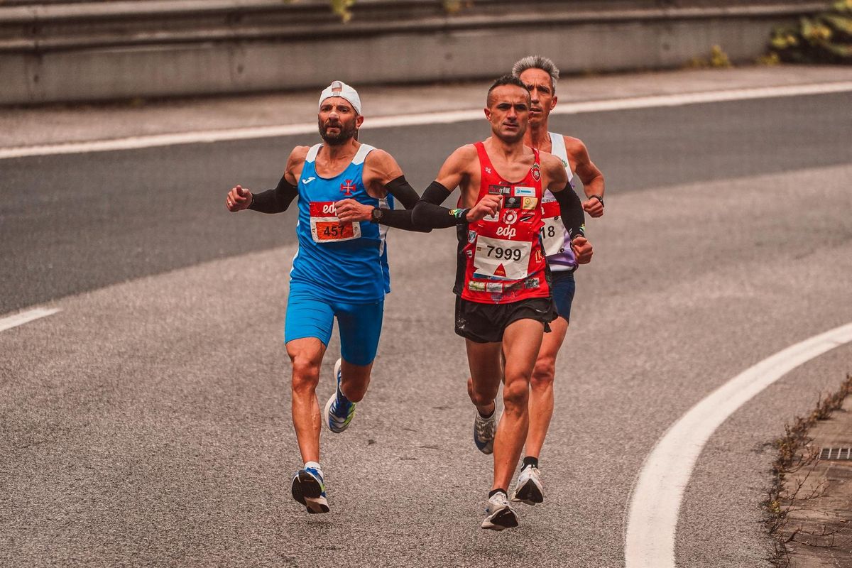 Three male runners competing in a marathon on a city road. Capturing endurance and athleticism.