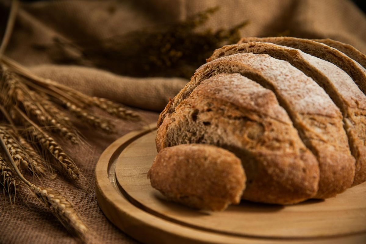 Freshly baked sliced bread on a wooden board with wheat grains for a rustic look.